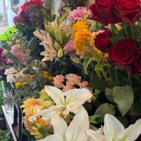 店頭に並ぶ赤いバラ・ユリ・ケイトウなどのお花